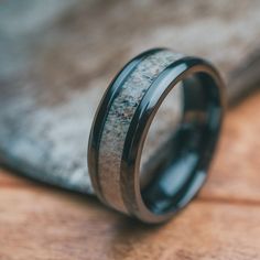 a black ceramic ring with antler wood inlaying the center on a wooden surface