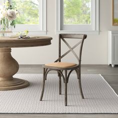 a dining room with a table and chair next to a flower vase on the floor