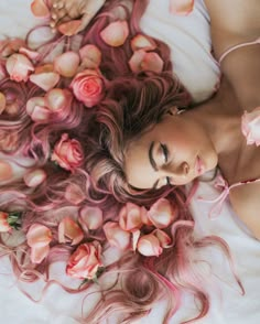 a woman laying on top of a bed covered in pink flowers next to her face