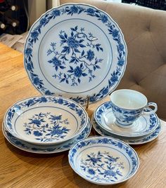 four blue and white plates sitting on top of a wooden table next to a couch