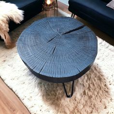 a wooden table sitting on top of a white rug next to a black couch and chair