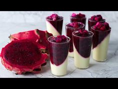 several glasses filled with dessert and garnished with raspberries on a marble surface