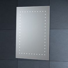 a bathroom mirror mounted on the wall above a sink with light reflecting off it's side