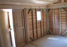 an unfinished room with wood paneling and windows