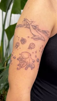 a woman's arm with an octopus and sea creatures tattoo on her left arm