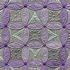 a close up view of a quilt with purple flowers on it