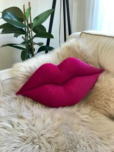 a white chair with a pink pillow on top of it and a potted plant in the background