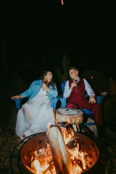 a man and woman sitting next to each other in front of an open fire pit