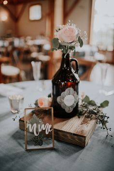 a table topped with a vase filled with flowers next to a wooden sign that says wine