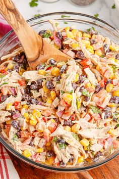 a bowl filled with chicken salad next to a wooden spoon