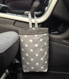 a gray and white polka dot bag sitting in the back seat of a car