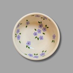 a white bowl with purple flowers painted on it