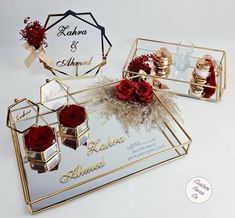 two mirrored trays with red roses in them on a white tablecloth, one is gold and the other is silver