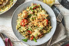 a bowl filled with rice and vegetables on top of a table next to utensils