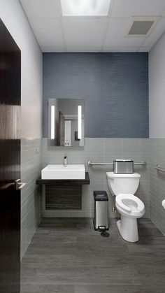 a bathroom with a toilet, sink and trash can in the middle of the room