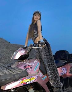 a woman sitting on top of a pink dirt bike next to a pile of junk