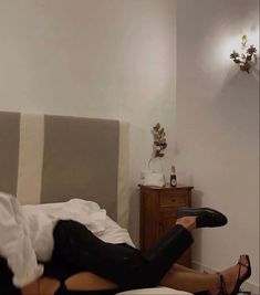 a woman laying on top of a bed wearing high heels