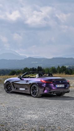 the bmw z4 roadster convertible is parked in a gravel lot with mountains in the background