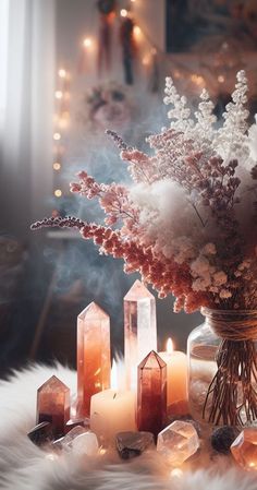 a vase filled with lots of flowers next to some rocks and candles on a table