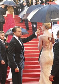 a man in a tuxedo holds an umbrella over a woman in a white dress