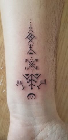 a small tattoo on the ankle of a person's foot, with an arrow and other symbols