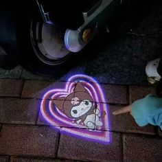 a person standing next to a sidewalk with a heart shaped chalk drawing on the ground