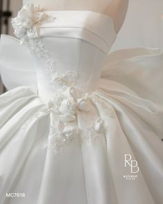 the back of a white wedding dress with flowers on it's waist and shoulder