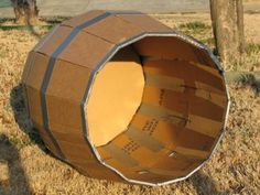 a cardboard barrel sitting in the middle of a field