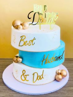 a three tiered cake with gold and blue decorations on it's sides, which reads happy birthday best husband and dad