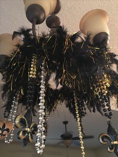 a chandelier hanging from the ceiling with black feathers and beads on it's arms