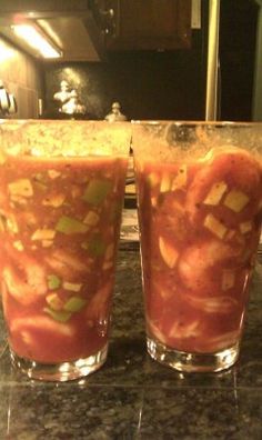 two glasses filled with food sitting on top of a counter next to a stovetop