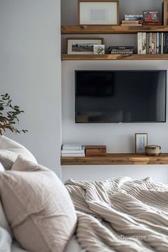 a flat screen tv sitting on top of a wooden shelf in a living room next to a bed