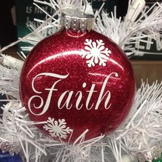 a red ornament with the word faith on it hanging from a white christmas tree