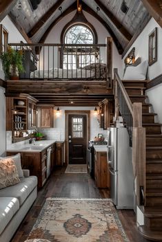 a living area with couches and a rug in front of a staircase leading up to a kitchen