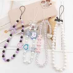 several different necklaces are displayed on a white table next to a cell phone case