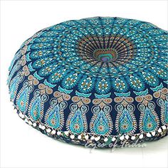 a blue and green round floor pillow with an intricate design on the front, sitting on top of a white surface