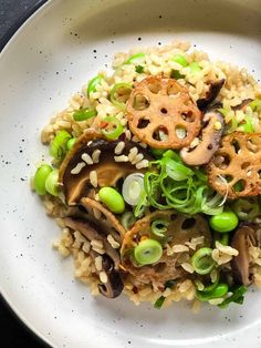 a white plate topped with rice, mushrooms and green beans next to a fork on top of a table