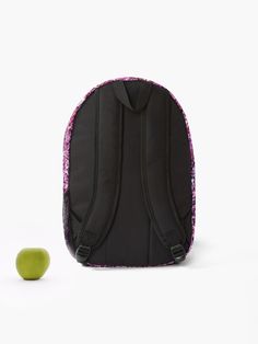 an apple sitting next to a black backpack with purple and pink sequins on it