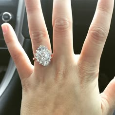 a woman's hand with a diamond ring on top of her finger in a car