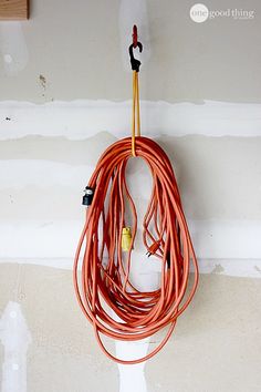 an orange cord hanging from a hook on a wall with some wires attached to it