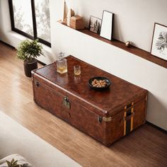 a brown suitcase sitting on top of a hard wood floor next to a table filled with drinks