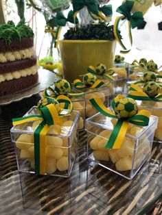 small clear boxes with yellow and green balls in them sitting on a table next to a potted plant