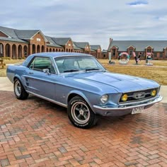 an old mustang car parked in front of a brick building