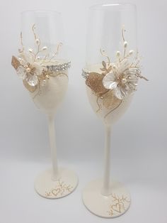 two wine glasses decorated with gold and white flowers