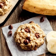 an oatmeal cookie with chocolate chips and bananas on a wooden table next to it