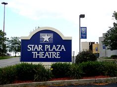 a blue sign that says star plaza theatre in front of some bushes and trees on either side of the road