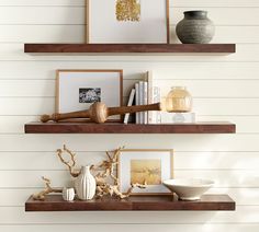 two wooden shelves with pictures, vases and other decorative items on top of them