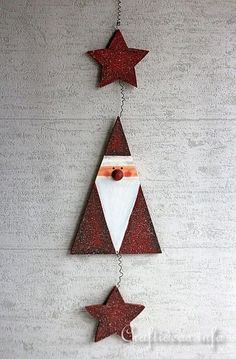 a santa clause hanging from the side of a christmas tree with red stars on it