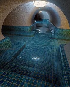 an indoor swimming pool with tiled walls and blue tiles on the floor, in front of a tunnel