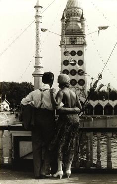 an old photo of two people standing on a pier